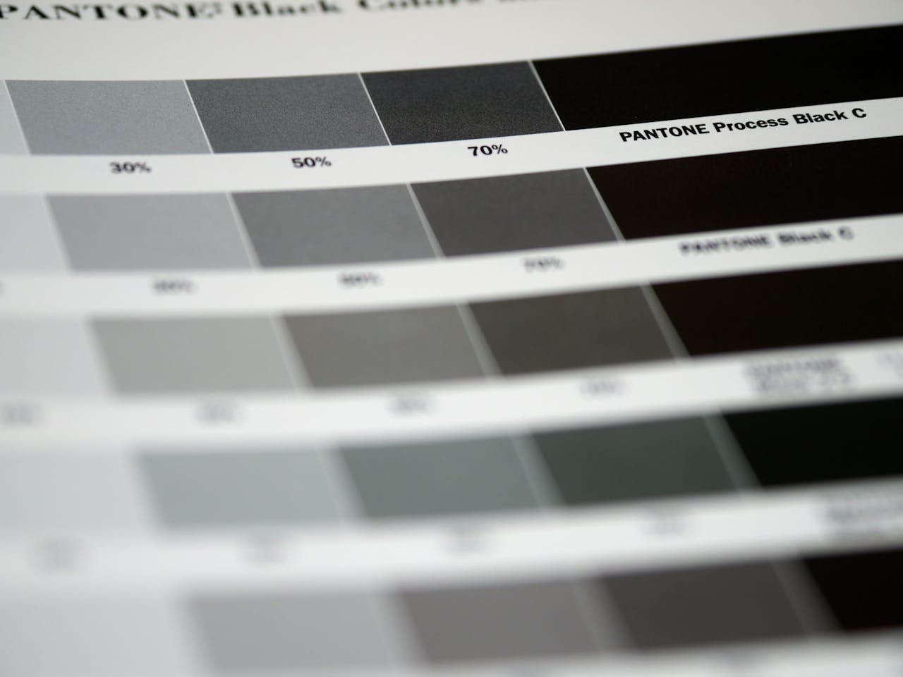 pexels-photo-8270924 Detailed close-up of Pantone black color swatches, featuring various shades and percentages.